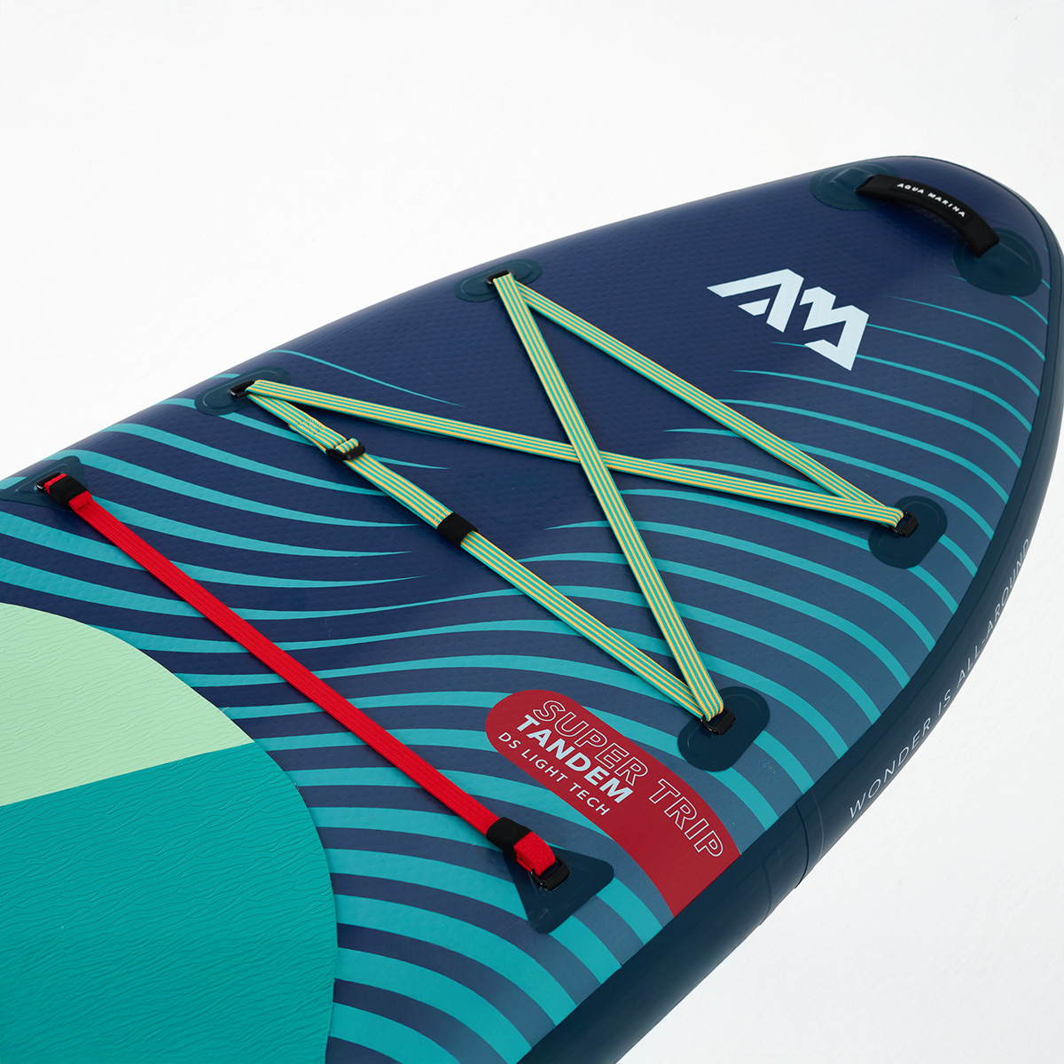 A close-up of the Aqua Marina SUPER TRIP TANDEM inflatable SUP, featuring an elastic bungee cord storage system, red safety strap, and a textured deck pad for enhanced grip.