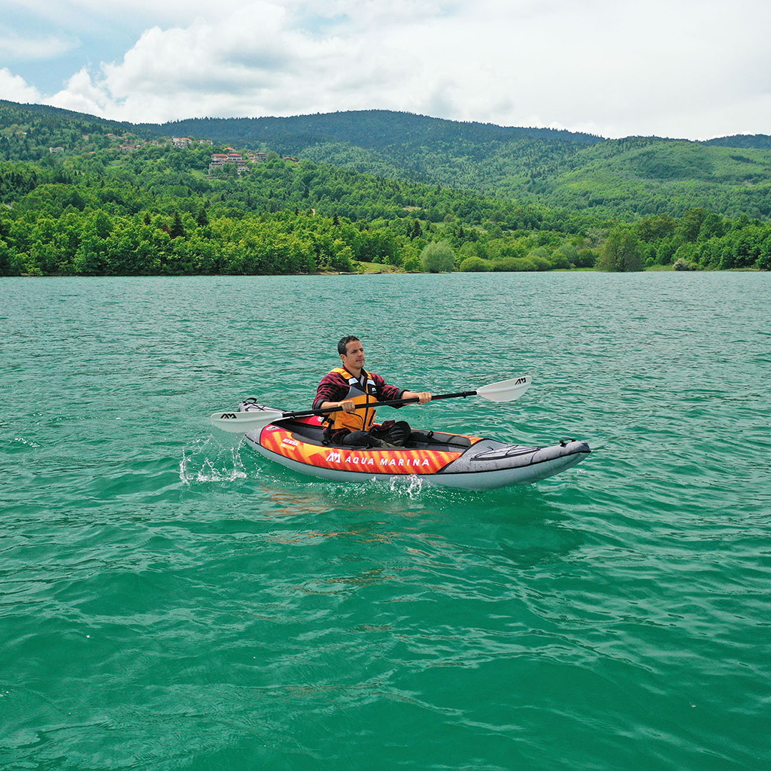 A person paddling the MEMBA single inflatable kayak by Aqua Marina on a lake.