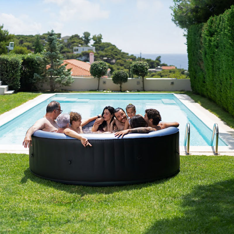 A family of seven enjoying the Aqua Marina BERGEN large round inflatable bubble spa in a backyard.