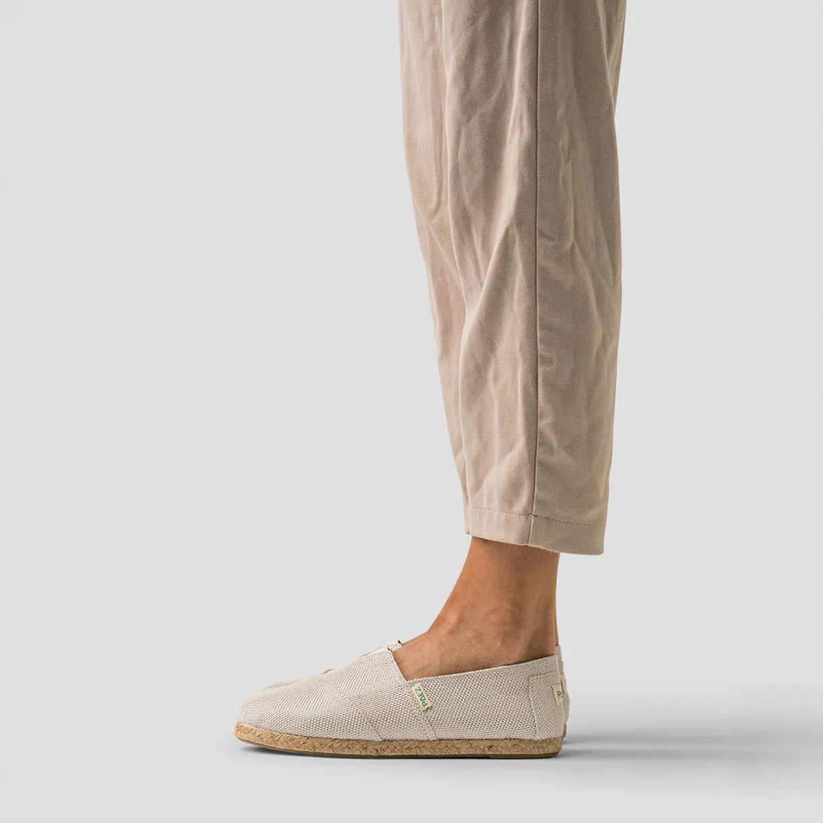 Classic Silver PAEZ espadrille shoes for women worn with light beige linen pants, shown from the side.