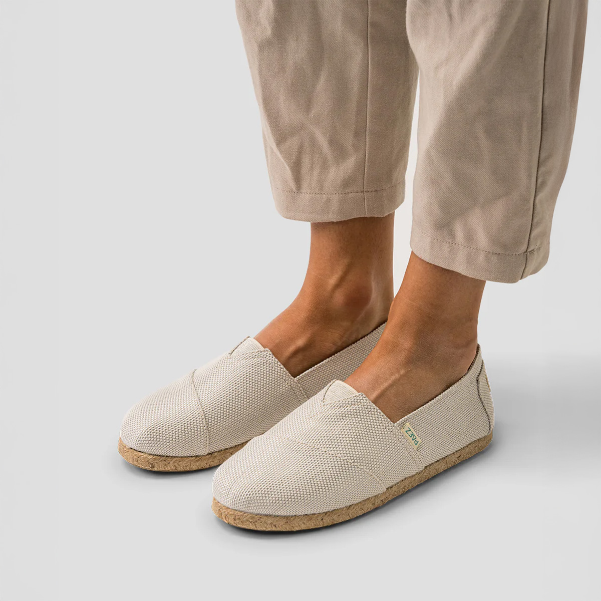 Pair of Classic Silver PAEZ espadrille shoes for women worn with light beige linen pants.