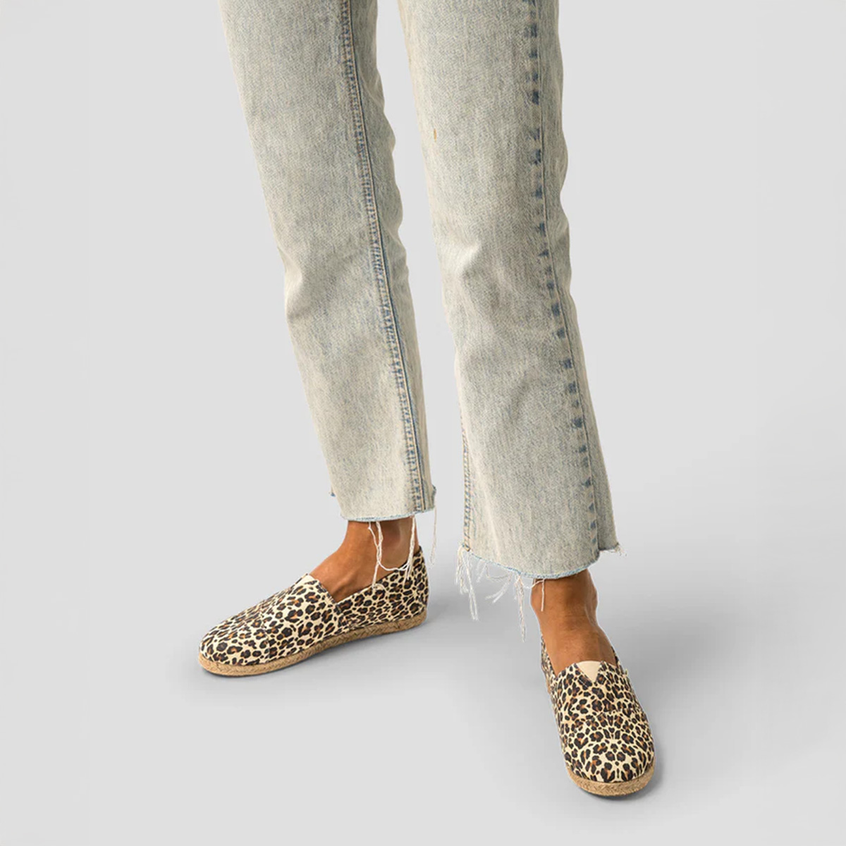 A pair of Leopard Print PAEZ Espadrilles worn with faded jeans, showcasing a chic and casual look.